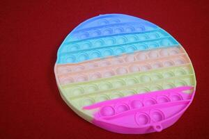färgrik fidget pop- leksaker, cirkulär form, som fungera till minska påfrestning. på röd bakgrund foto