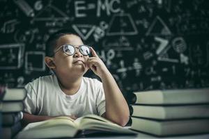 pojkar med glasögon skriver böcker och tänker i klassrummet