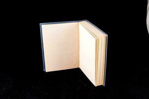 en bok öppen på en svart yta med en vit objekt foto