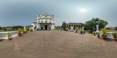 full hdri 360 panorama av portugisiska katolik kyrka i djungel bland handflatan träd i indisk tropisk by i likriktad utsprång med zenit och nadir. vr ar innehåll foto