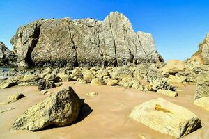 en klippig strand med stor stenblock och en blå himmel foto