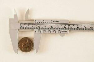 en tjocklek är innehav en mynt på en vit yta foto