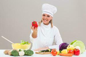 kvinna kock som visar peppar medan framställning friska måltid foto