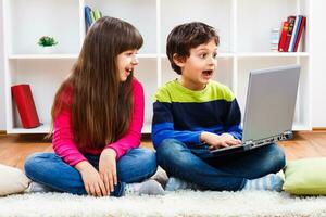 två barn använder sig av bärbar dator foto