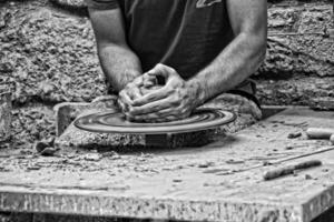 händer av en krukmakare i en närbild av en matare arbetssätt på en lera pott foto