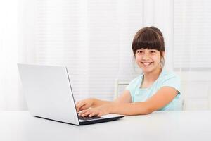 söt liten flicka är använder sig av bärbar dator foto
