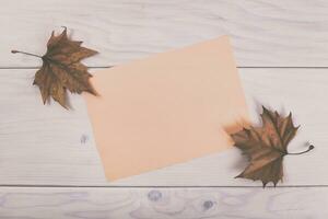 höst löv och tom papper på en trä- tabell topp se foto