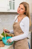 arg kvinna stående i henne kök medan framställning måltid foto