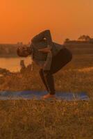 man håller på med yoga på solnedgång med stad se foto