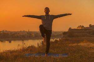 man håller på med yoga på solnedgång med stad se foto