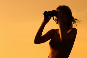 kvinna åtnjuter i solnedgång med kikare foto