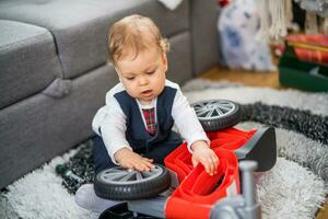 söt liten bebis pojke spelar och reparation hans först cykel foto