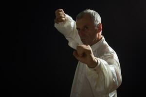 senior man åtnjuter övning tai chi inomhus- foto