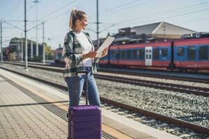 Lycklig kvinna använder sig av digital läsplatta på en tåg station foto