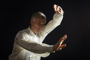 senior man åtnjuter övning tai chi inomhus- foto