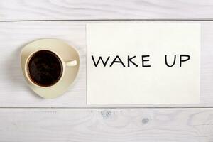 vakna upp text och kopp av kaffe på en trä- tabell foto