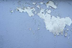 gammal cement vägg skala exteriör bakgrund med blå måla peeling låg kvalitet, knäckt vägg foto