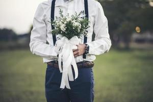 brudgummen hand som håller kärlekens blomma under bröllopsdagen