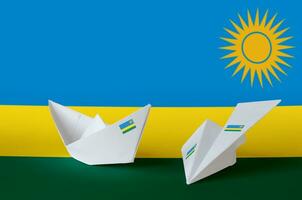 rwanda flagga avbildad på papper origami flygplan och båt. handgjort konst begrepp foto