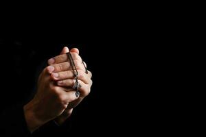 stilig man sitta bön på svart bakgrund. hans händer är bön- för guds välsignelser. foto