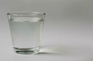glas av dricka vatten på klar bakgrund för kopia Plats foto