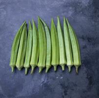 färsk organisk grönsaker damens finger eller okra på de mörk betong golv foto