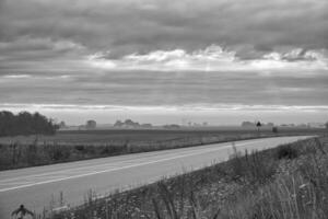 Land väg med kurva leder genom jordbruks fält i svart och vit foto