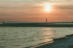 spektakulär solnedgång på de strand med små båtar i Sol strålar foto