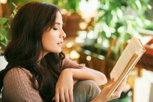 porträtt av ung kvinna läsning bok på balkong foto