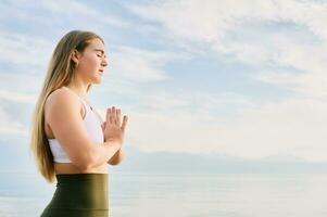 utomhus- porträtt av ung skön kvinna praktiserande yoga förbi de sjö foto
