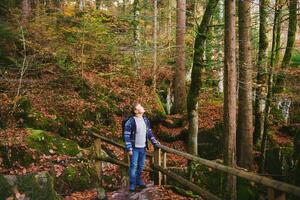 utomhus- porträtt av Lycklig unge pojke vandring i höst skog, bär ryggsäck foto