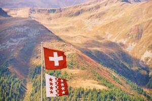 swiss flagga och flagga av kanton av valais mot swiss alpina berg foto