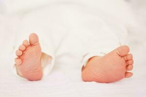 stänga upp bild av mycket liten nyfödd bebis fötter foto
