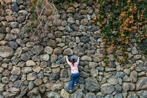 en ung flicka klättrar över de stenar på topp av en kulle foto