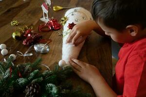 de barn sitter på de tabell och gör en jul träd han själv, hantverk. sida se. själv. foto