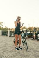 skön flicka med en cykel, en telefon och hörlurar foto