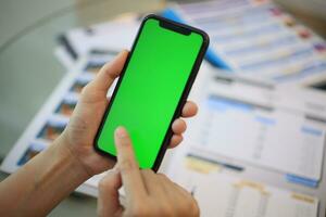 telefon grön skärm i hand, hand innehav smartphone grön skärm i hus, använder sig av mobil telefon grön skärm foto
