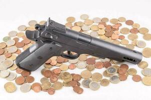 en pistol och mynt på en vit bakgrund foto