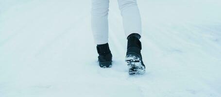resande gående på de snö, närbild vattentät stövlar eller skor under vandring på snöig skog. vinter- säsong foto