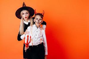 kvinna och pojke i djävulens maskeradsminkning som visar förundranskänsla. halloween koncept foto