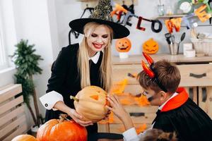 mamma och son funderar på pumpa och har roligt hemma. -halloween koncept foto