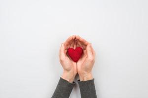 textilrött hjärta i kvinnahand på pastellbakgrund foto