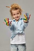 skön liten flicka med en målad händer är Framställ på en grå bakgrund. foto