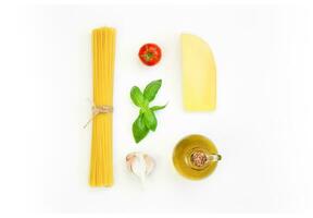 spaghetti, tomat, basilika, parmesan, vitlök, oliv olja på en vit bakgrund. italiensk kök. foto