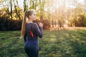 leende, vacker blond tjej gör hopprep utomhus. bakåtsikt foto