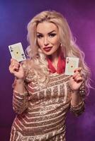 blond kvinna med en perfekt frisyr och ljus smink är Framställ med spelar kort i henne händer. kasino, poker. foto