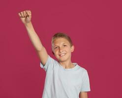 närbild porträtt av en blond Tonårs pojke i en vit t-shirt Framställ mot en rosa studio bakgrund. begrepp av uppriktig känslor. foto
