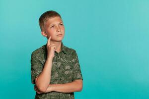 närbild porträtt av en blond Tonårs pojke i en grön skjorta med handflatan skriva ut Framställ mot en blå studio bakgrund. begrepp av uppriktig känslor. foto