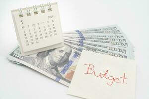 budget text på papper, oss dollar med 2024 jan kalender på en vit bakgrund. finansiera, pengar förvaltning begrepp. foto