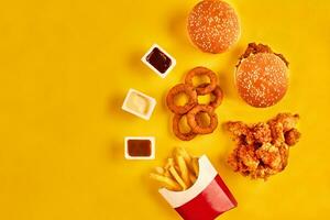 topp se hamburgare, franska frites och friterad kyckling på gul bakgrund. kopia Plats för din text. foto